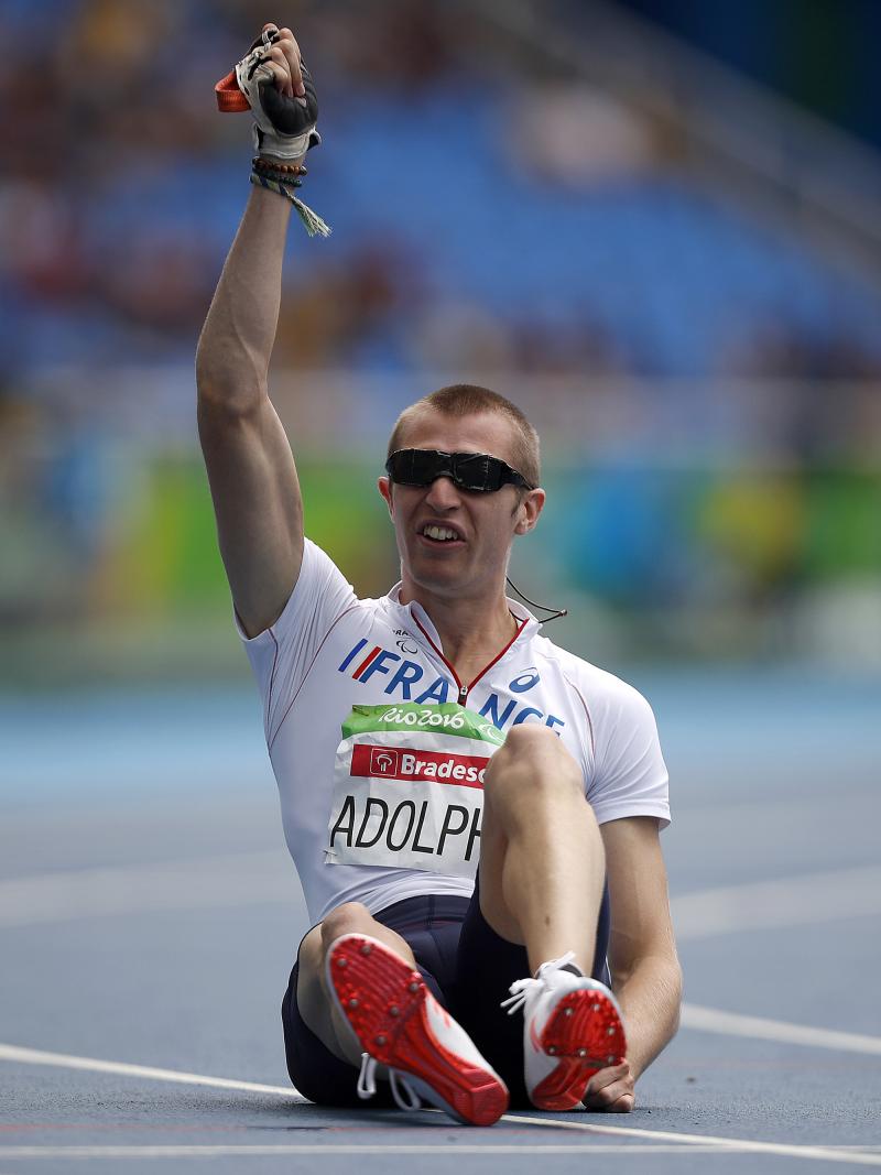 Man sitting on a track raising one arm