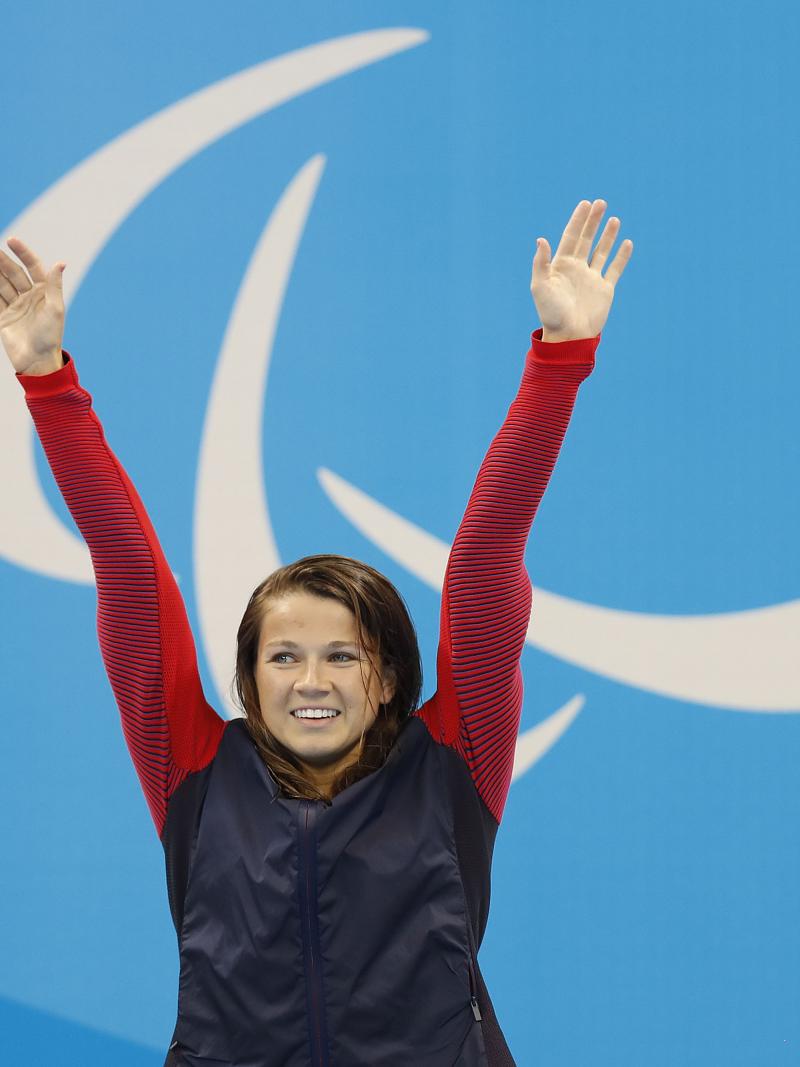 Upper body of a woman, raising her arms in the air