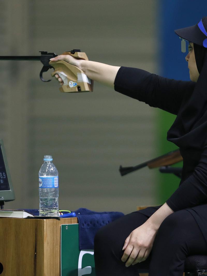 Woman with black headscarf aiming with a weapon