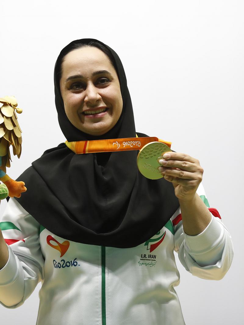 Woman with headscarf poses with medal and mascot in her hand