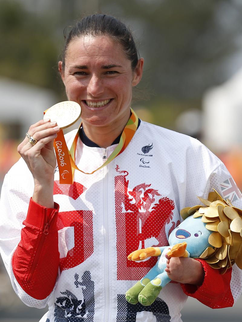 Woman in track suit showing a medal to the camera