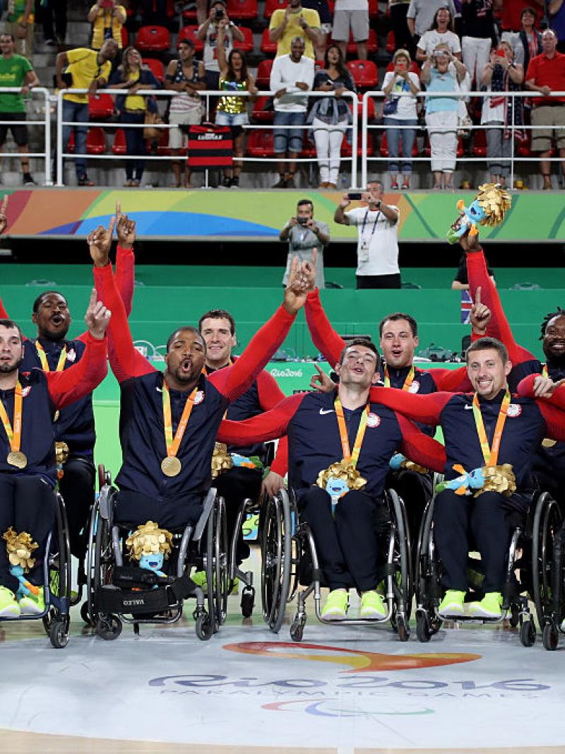 Group of men in wheelchairs celebrate after winning gold.