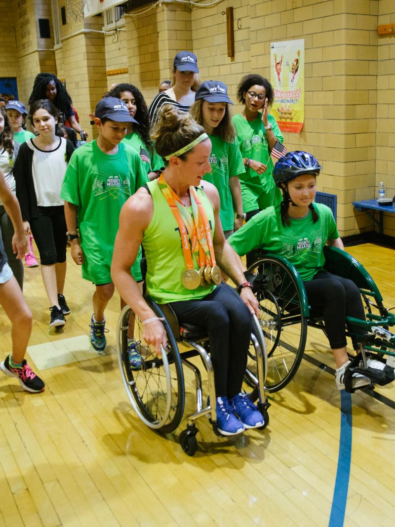 An athletes shows a young girl how to use a racing wheelchair