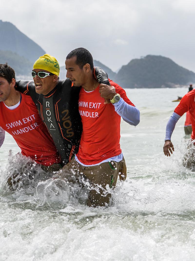 Mohamed Lahna MAR (left) and Stephane Bahier FRA are aided out of the water during the Men's PT2 Triathlon competition at Fort Copacabana.