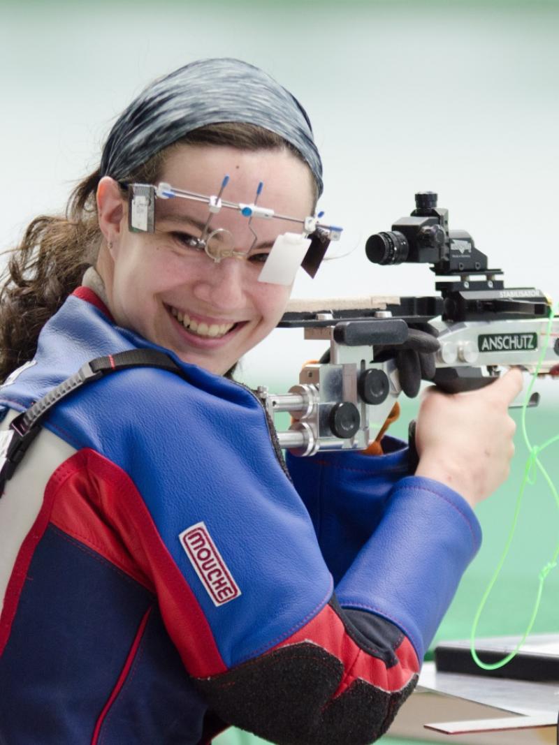 Woman in shooting range, looking back over her shoulder, smiling