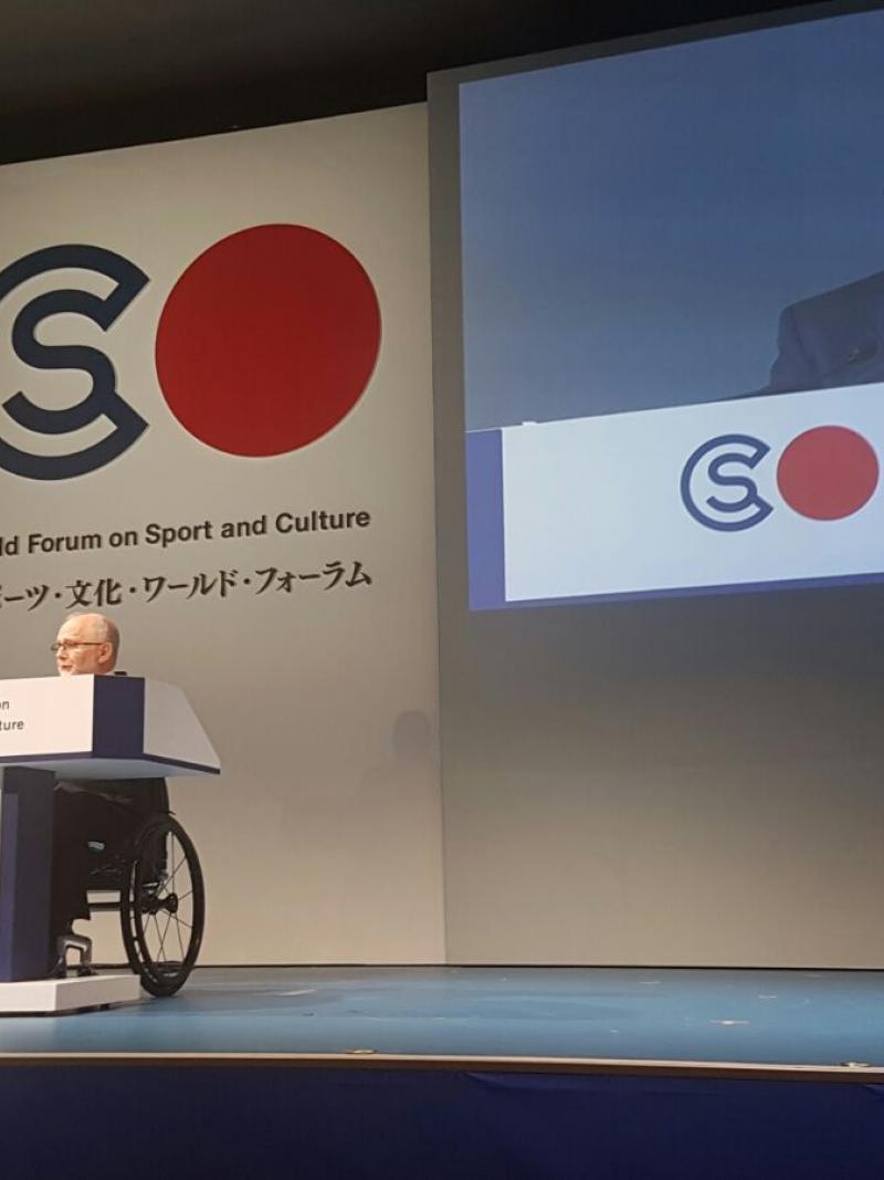 Man in wheelchair on stage giving a speech