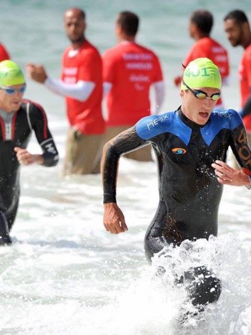 Two men in wet suits coming out of the water