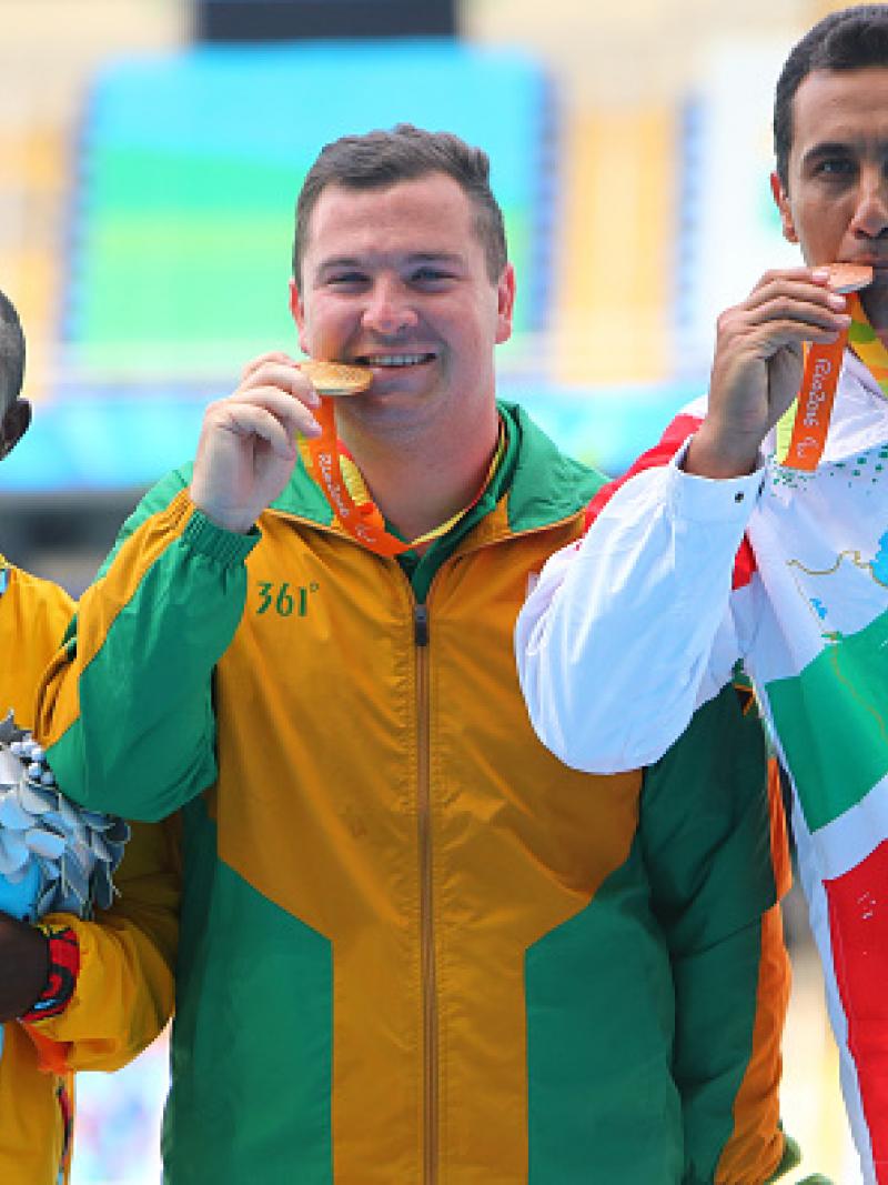 Three men on podium, with their medals