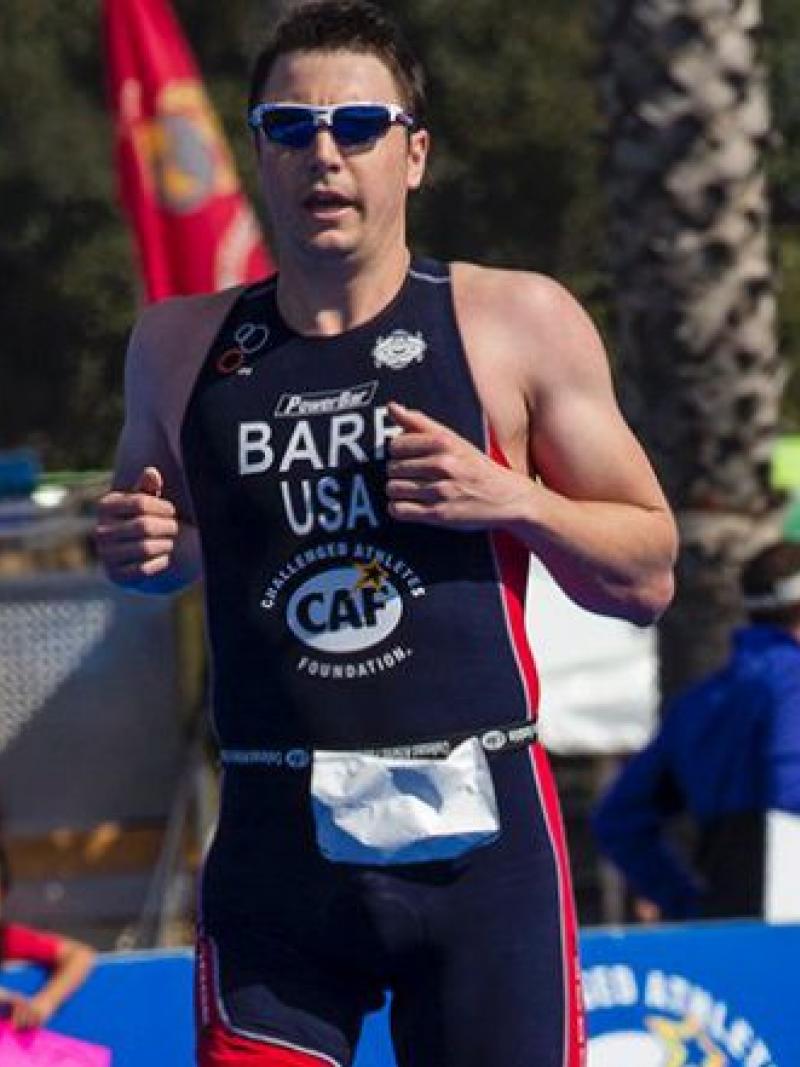 A picture of a man with one prosthesis running and crossing a finish line