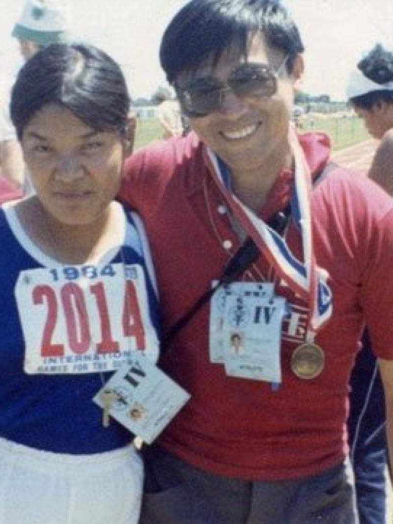 Two people posing for a photo in track clothes