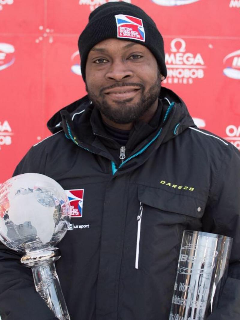 Profile picture of a man who smiles and holds a trophy in his hands