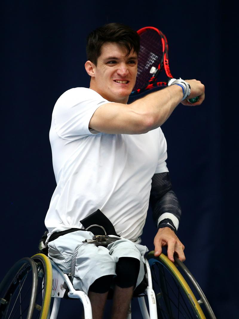 Wheelchair tennis player hits a ball.