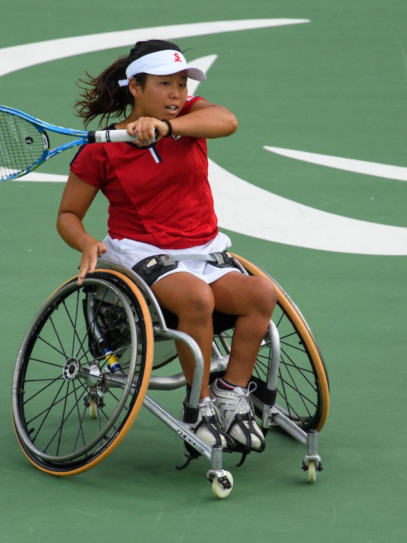A Japanese wheelchair tennis player is hitting the ball.