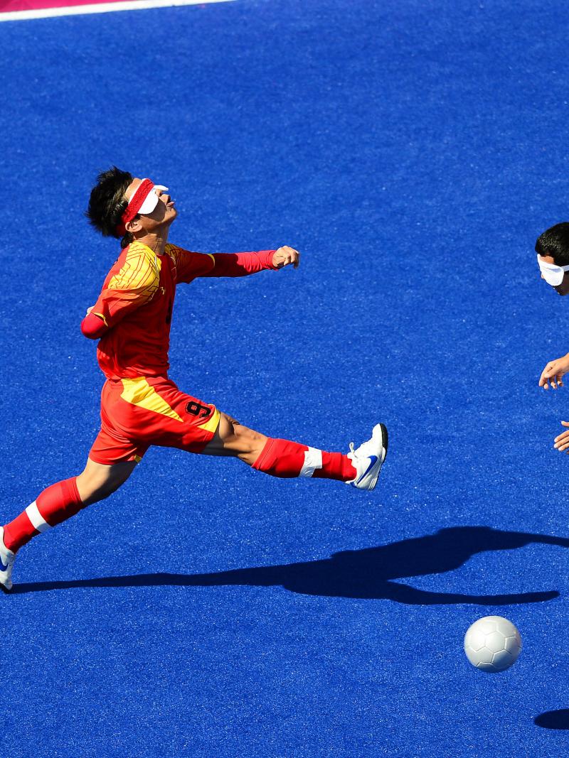 A Chinese blind football player kicks the ball.