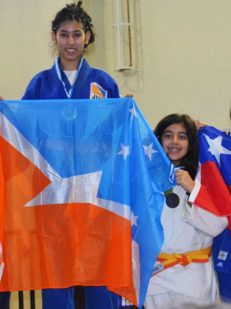 Rocio Ledesma stands on top of the podium whilst holding the flag from her province.