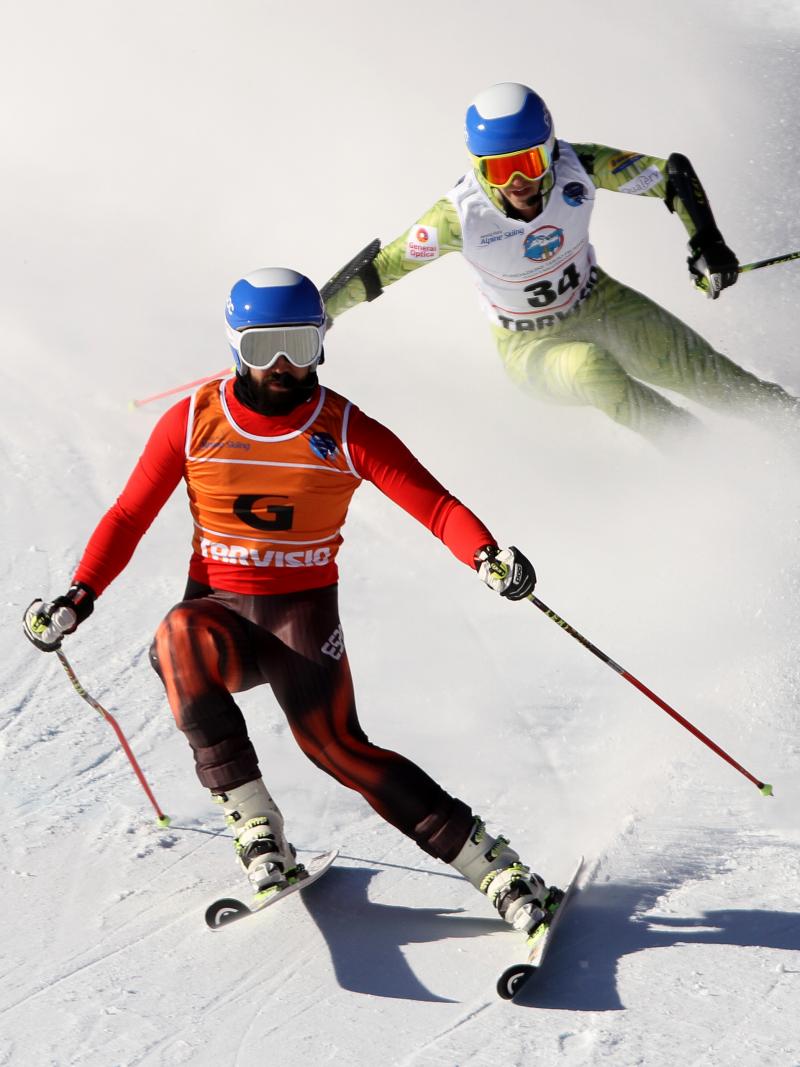 Vision impaired skier and his guide going down a slope