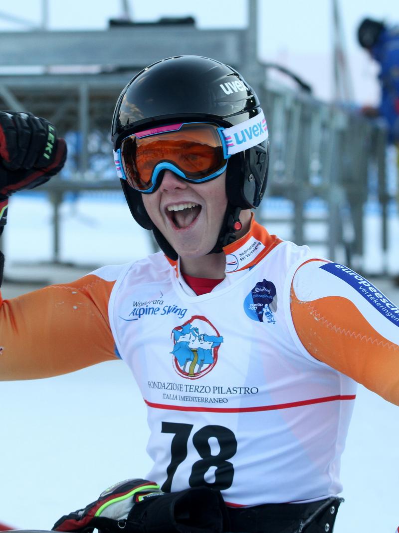 Man in ski helmet and goggles smiles in a sit ski