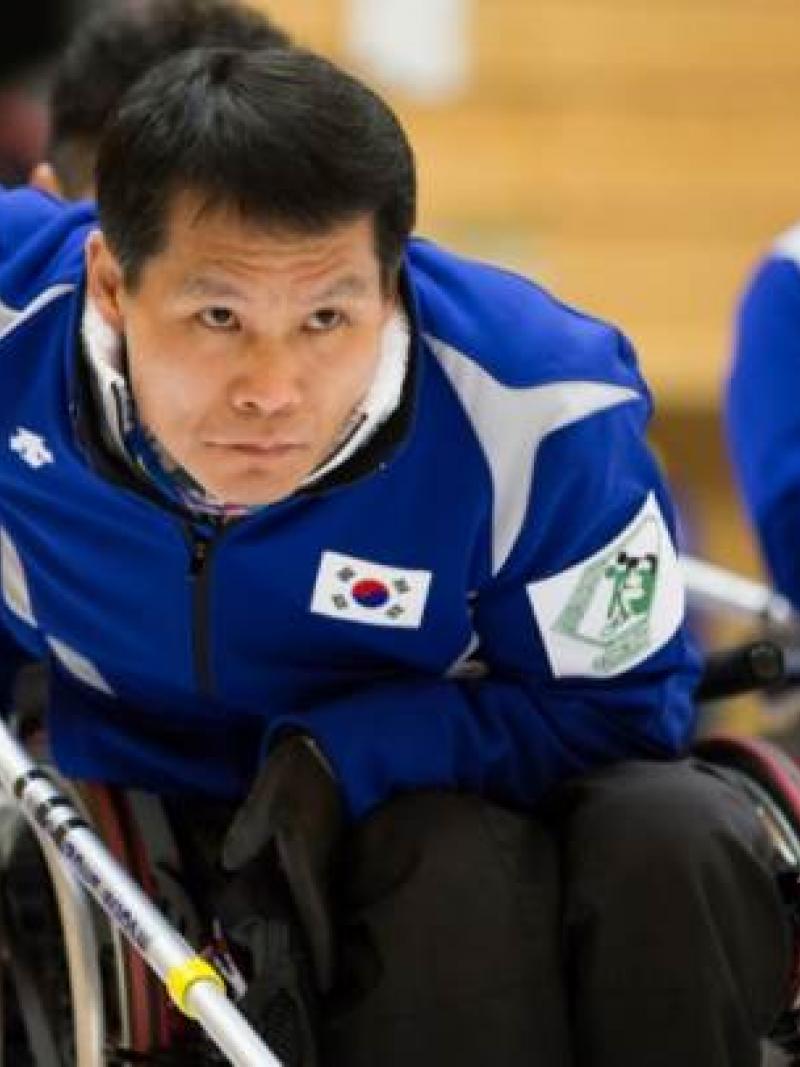 An athlete in a wheelchair competing in a game of curling. 