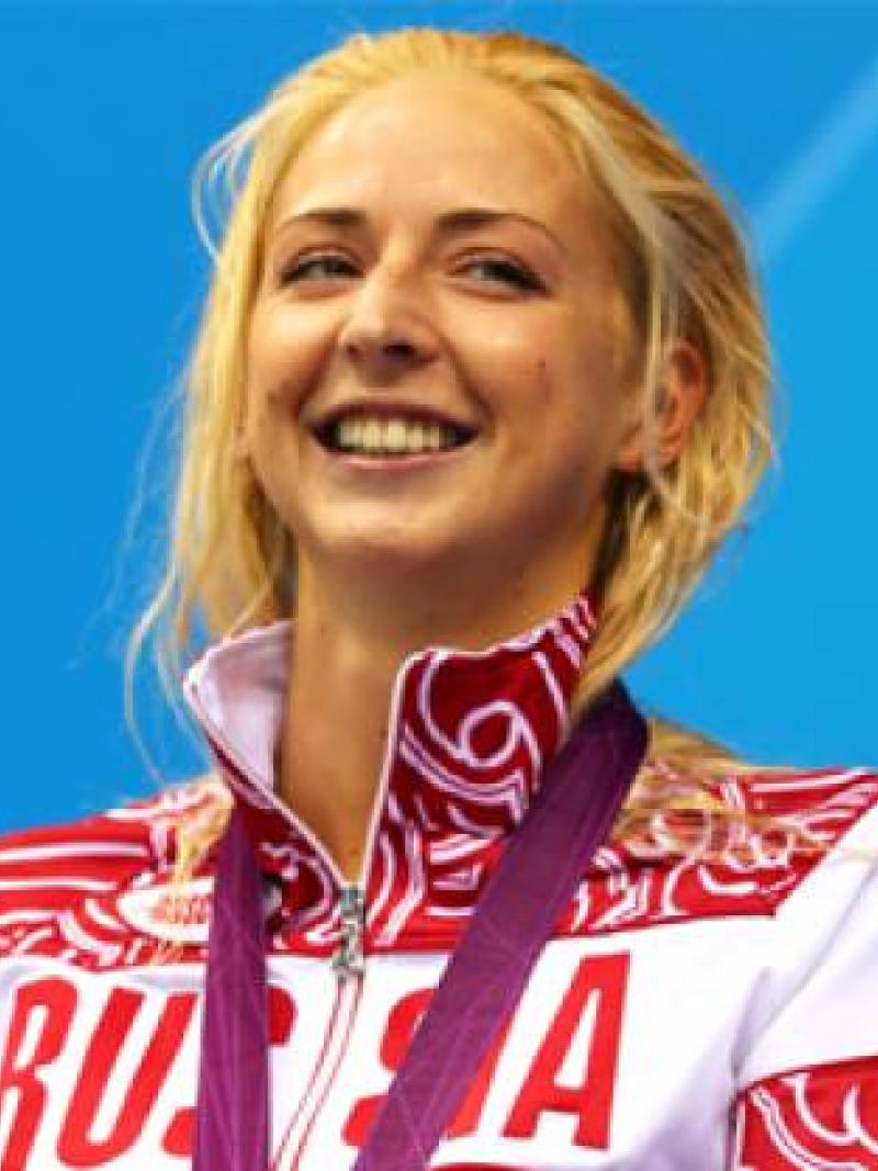 A picture of a woman standing with a silver medal around her neck