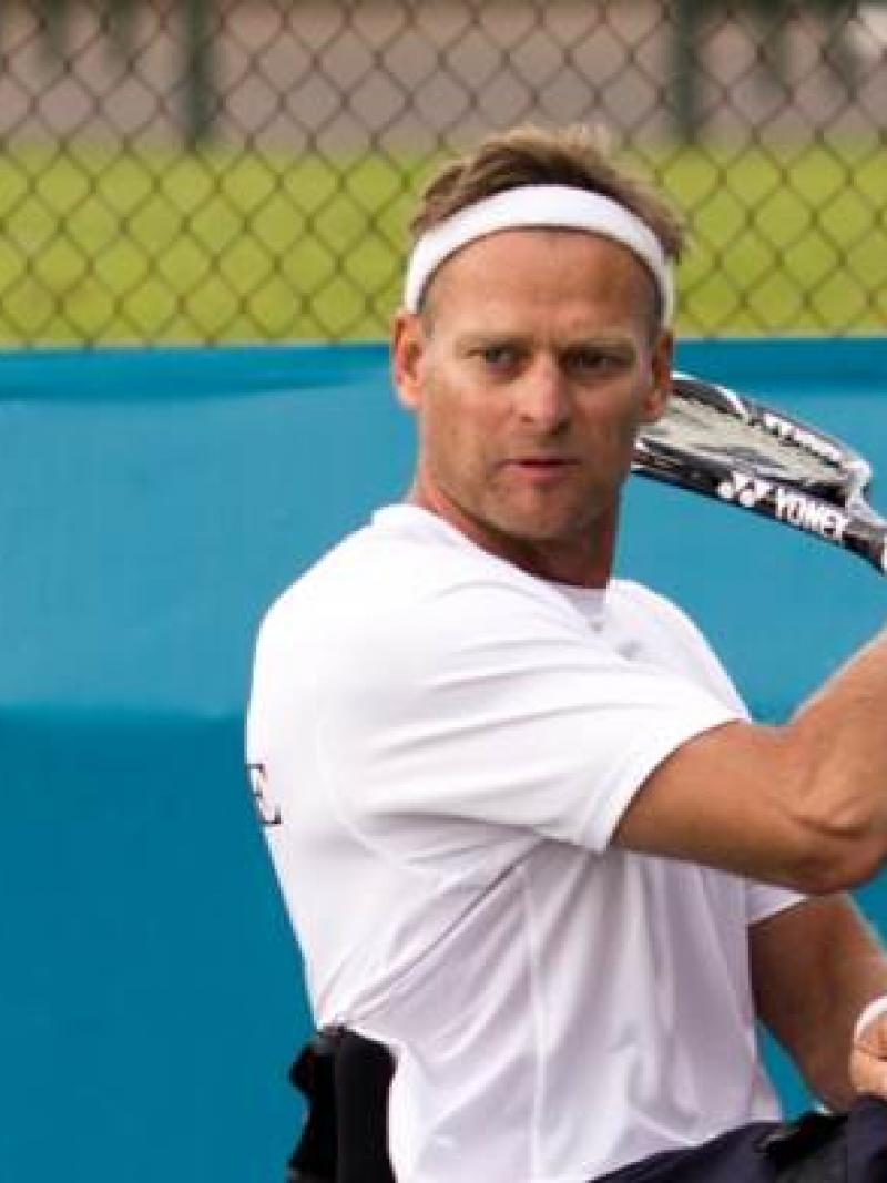 A picture of a man in a wheelchair playing a backhand