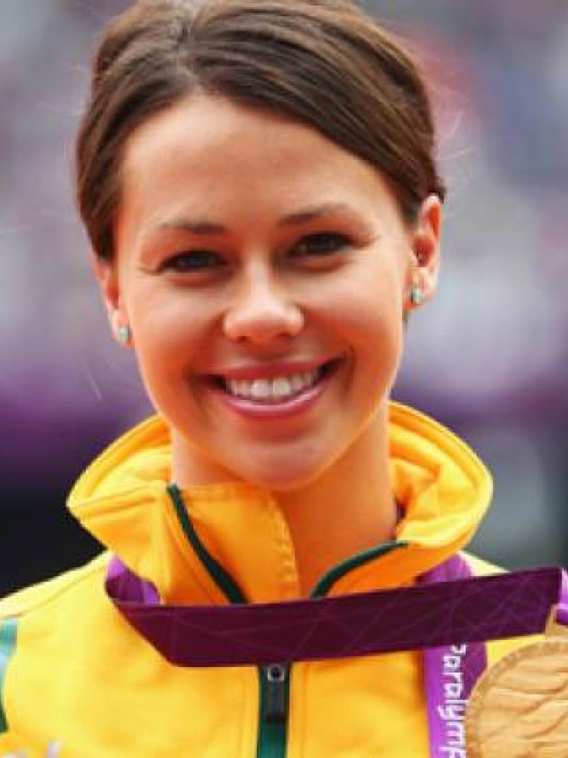 A picture of a woman showing her gold medal hanging around her neck