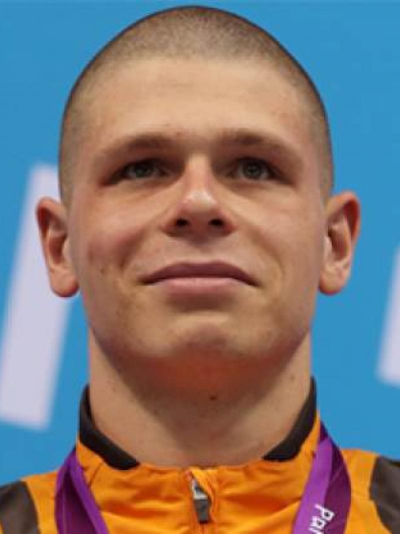 A picture of a man with a gold medal around his neck during a medal ceremony