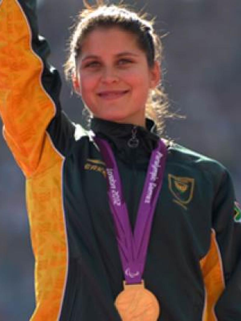 A picture of a woman with a gold medal around her neck during a medal ceremony.