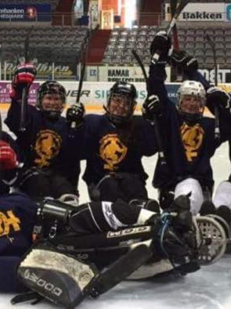 Group of female sledge hockey players pose for a photo