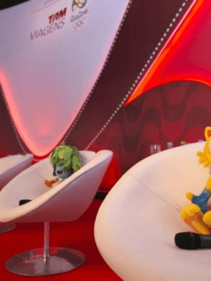 Shot of a stage with white chairs and the Rio mascots on them