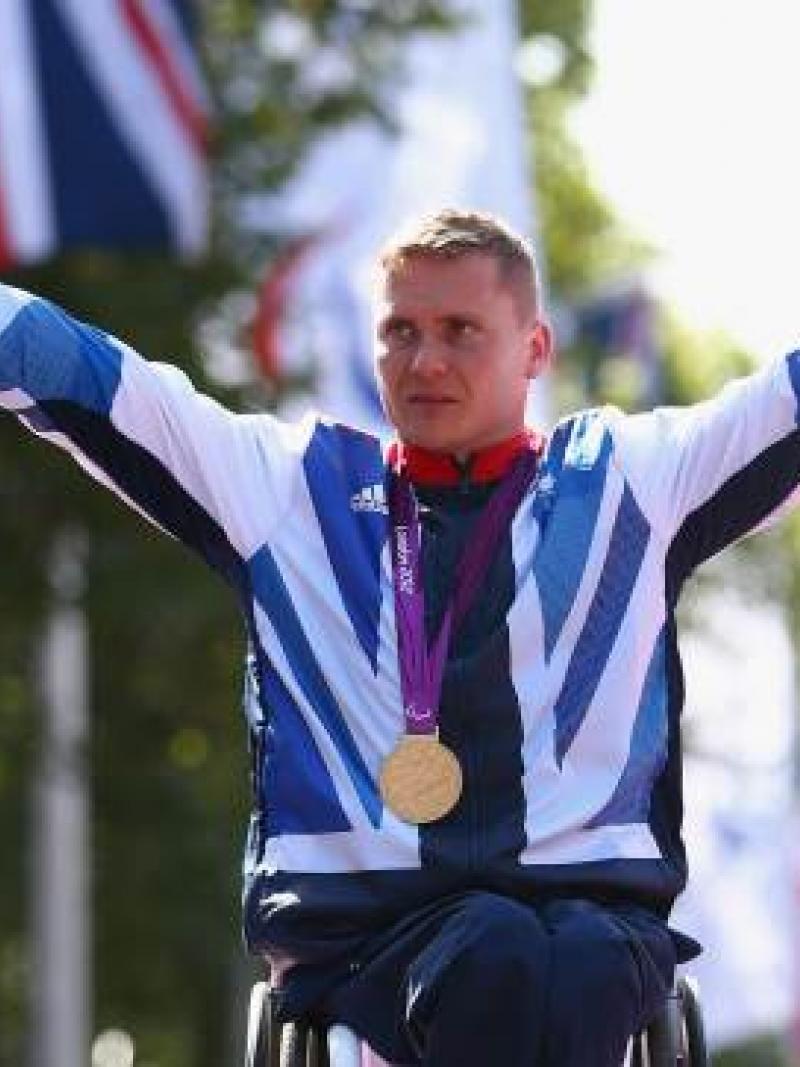A picture of a man in wheelchair celebrating his victory with a gold medal around his neck