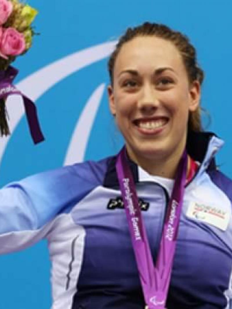 A picture of a woman in a wheelchair showing her gold hanging around her neck