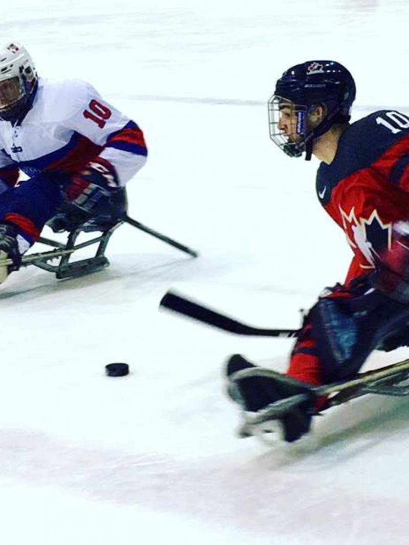 Two Para ice hockey players duel on the ice