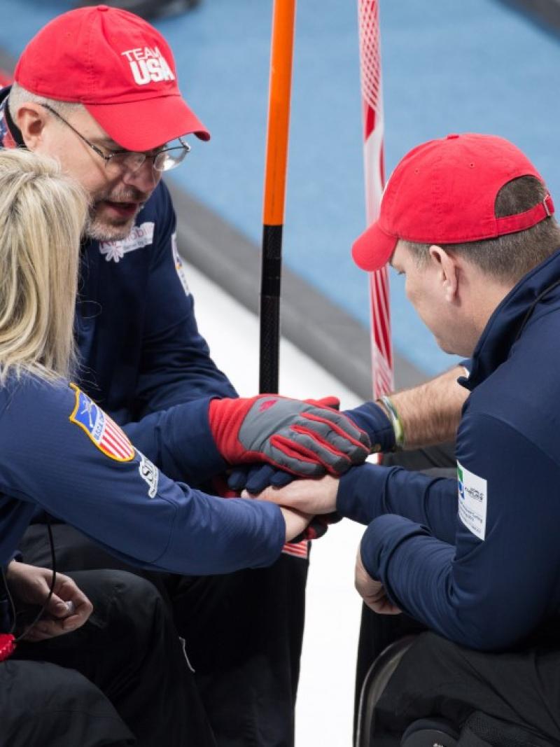 Group of people in blue jackets and wheelchairs forming a circle