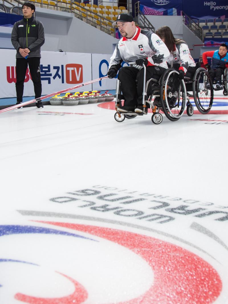 People in wheelchairs on ice rink, curling