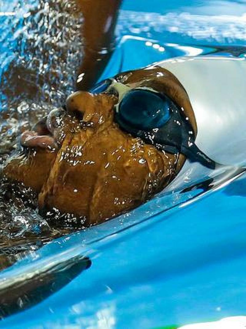 Athlete in water with goggles competes in backstroke