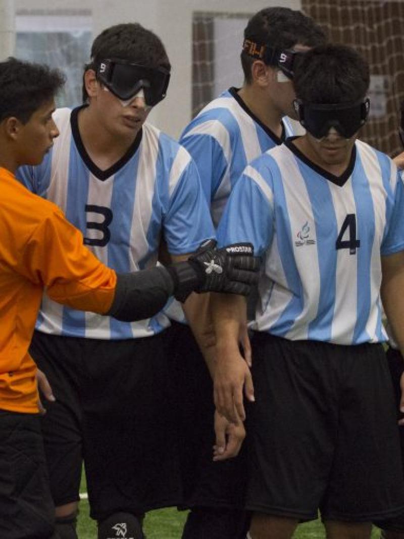A blind football team organise themselves on the pitch