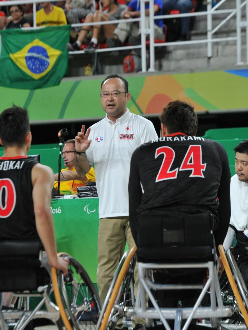 Coach surrounded by his men's wheelchair basketball team giving instuctions