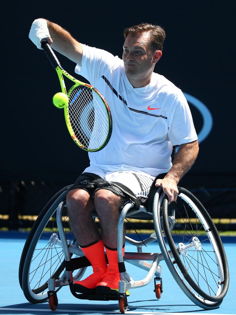 Man in wheelchair returns a tennis ball