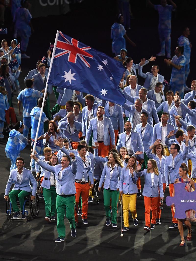 A group of Para athletes march into a stadium with one athlete holding the Australian flag during the Rio 2016 Opening Ceremony