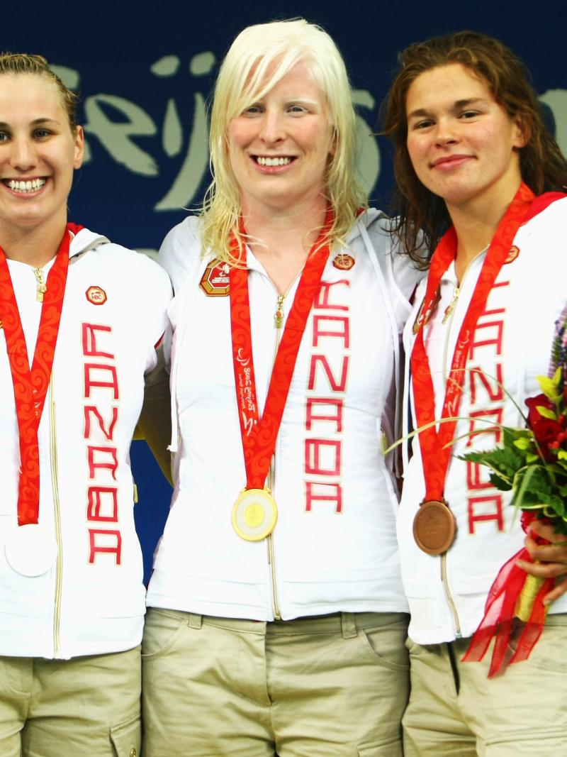 Three female swimmers pose for a photo