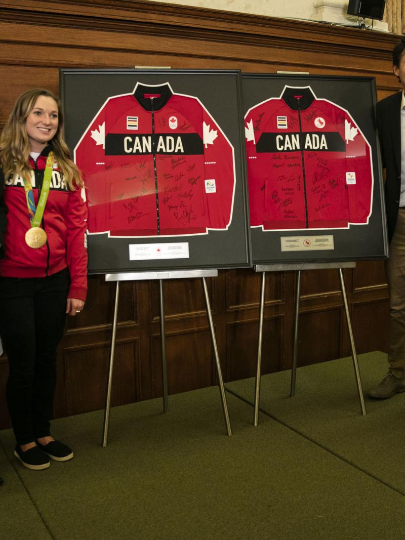 Four people stand between two signed jerseys, posing for a photo