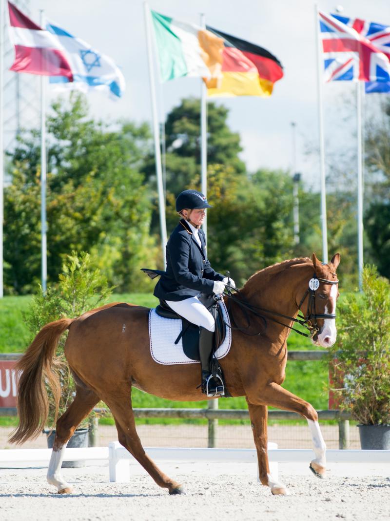 Woman riding a horse with various nation's flags in the background