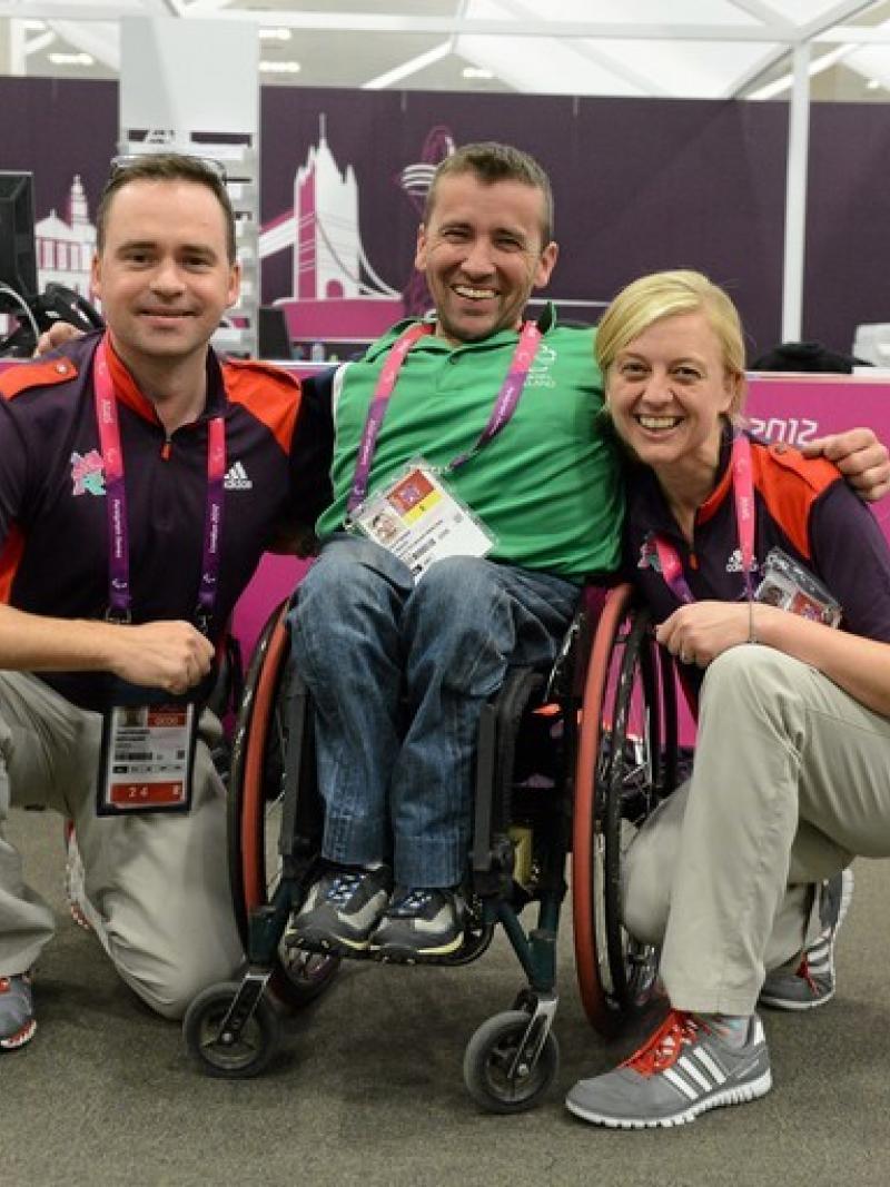 Man in wheelchair between two people posing for photo
