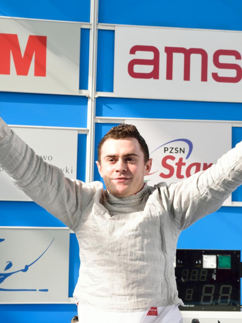 Man in wheelchair holds up arms celebrating