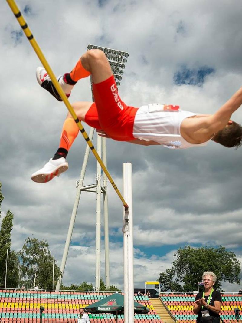 man jumps horizontally over high jump bar
