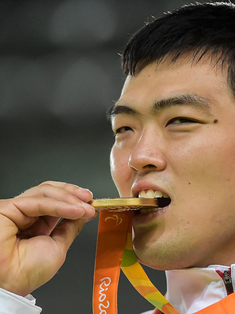 man bites gold medal in celebration