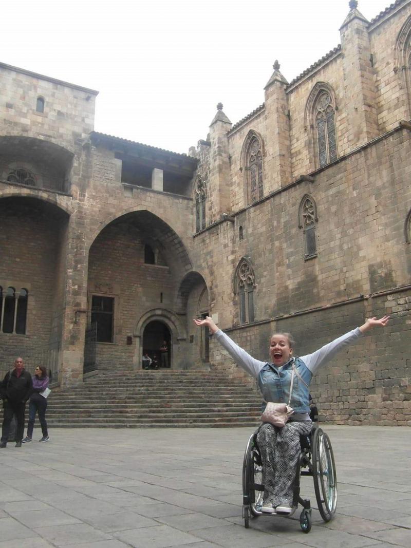 woman in wheelchair smiling with arms outstretched