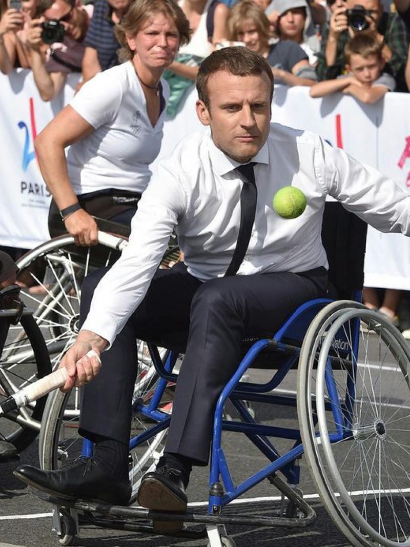 man in suit plays tennis in wheelchair