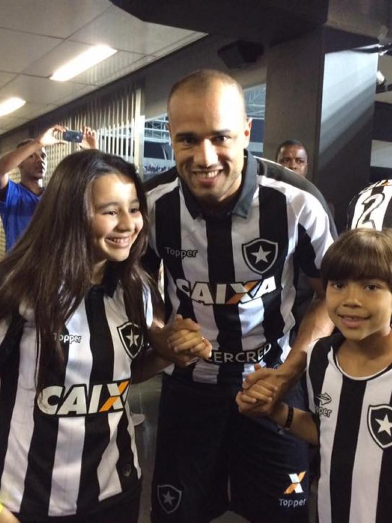 A footballer hugs his son and daughter before a game