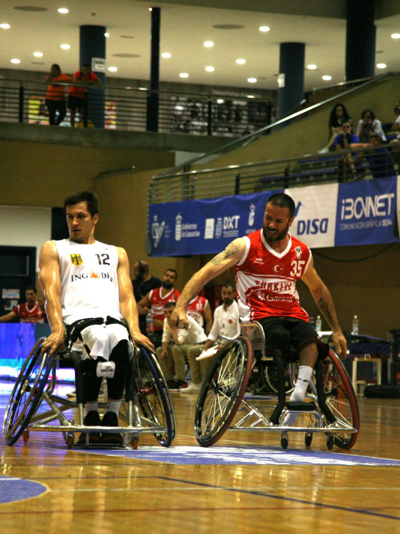 a group of men in wheelchairs challenge for a basketball